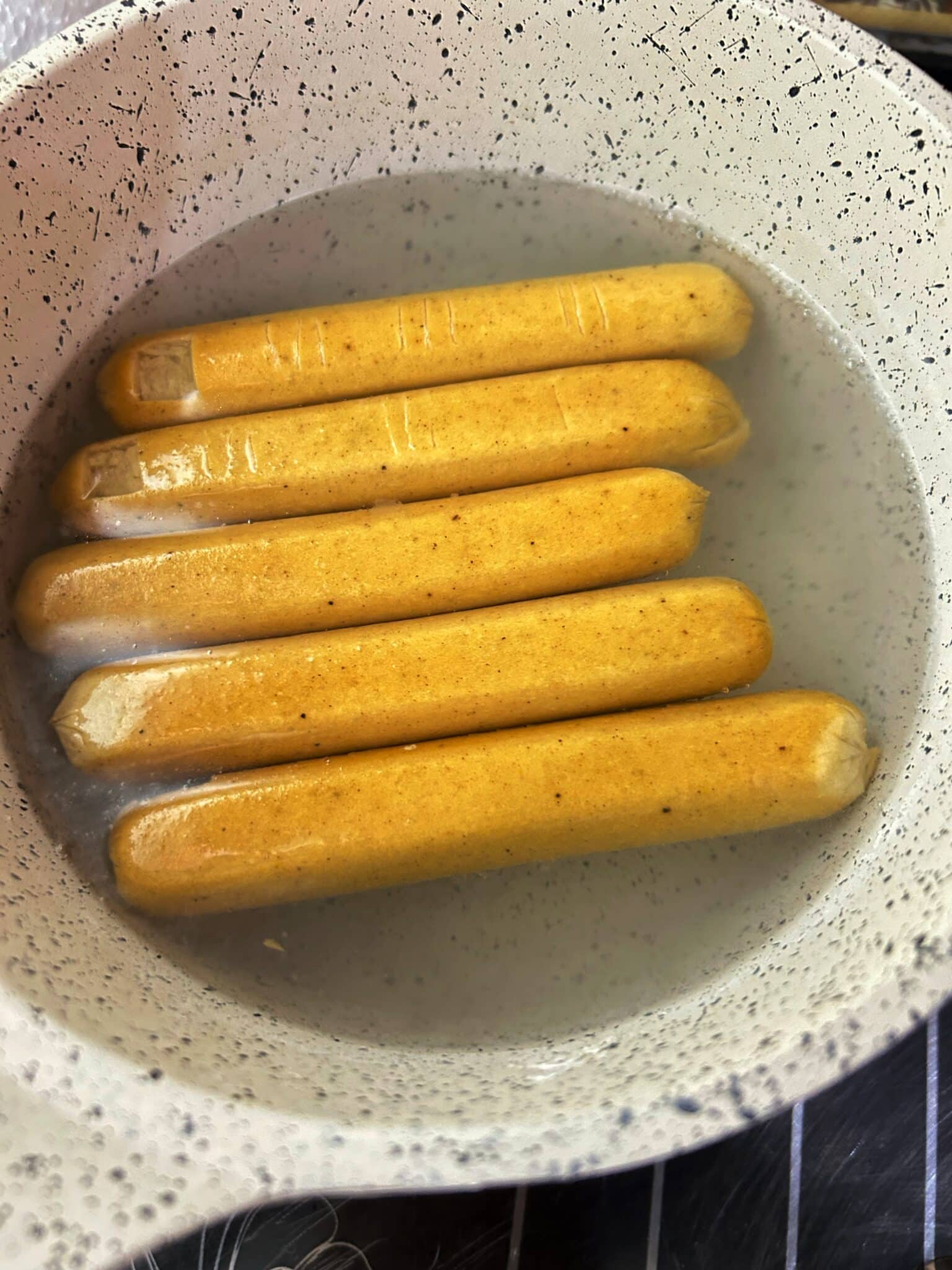 Hot dogs boiling in a pot of water on the stove Hot dogs boiling in a pot of water on the stove