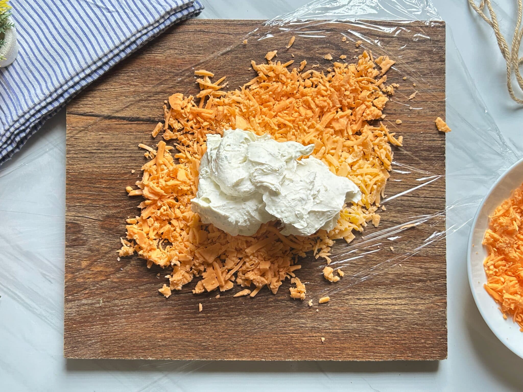 Cream cheese mixture placed on cheddar-covered plastic wrap Cream cheese mixture placed on cheddar-covered plastic wrap