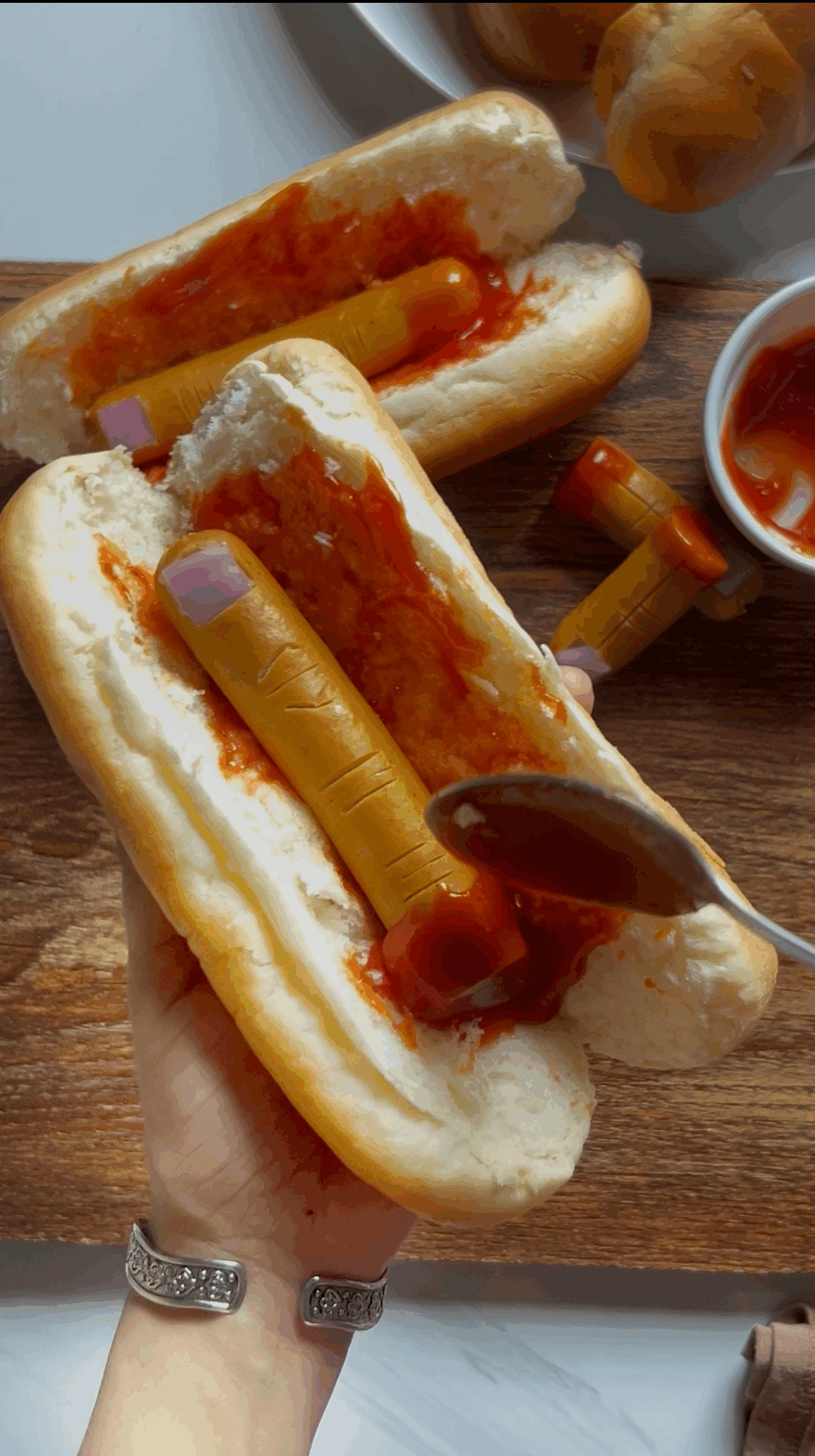 Hot dog buns with ketchup spread, ready for placing hot dog fingers inside Hot dog buns with ketchup spread, ready for placing hot dog fingers inside