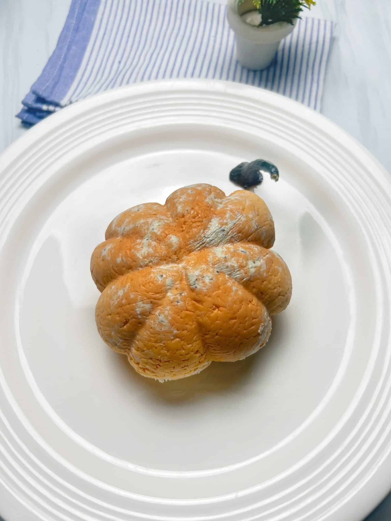 Pumpkin-shaped cheeseball unwrapped and topped with pepper stem Pumpkin-shaped cheeseball unwrapped and topped with pepper stem