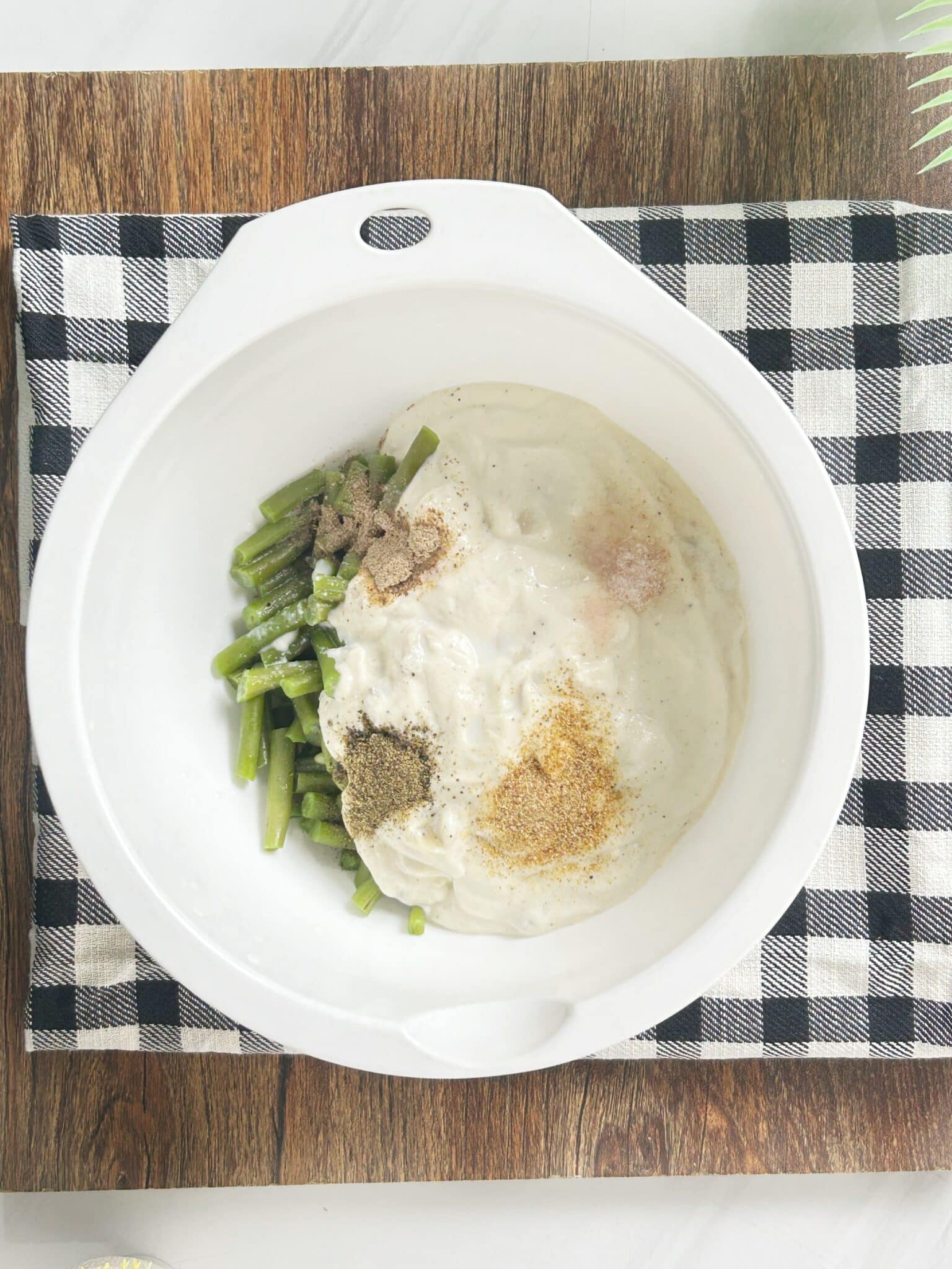 Green beans mixed with cream of mushroom soup, spices, and milk in a bowl Green beans mixed with cream of mushroom soup, spices, and milk in a bowl