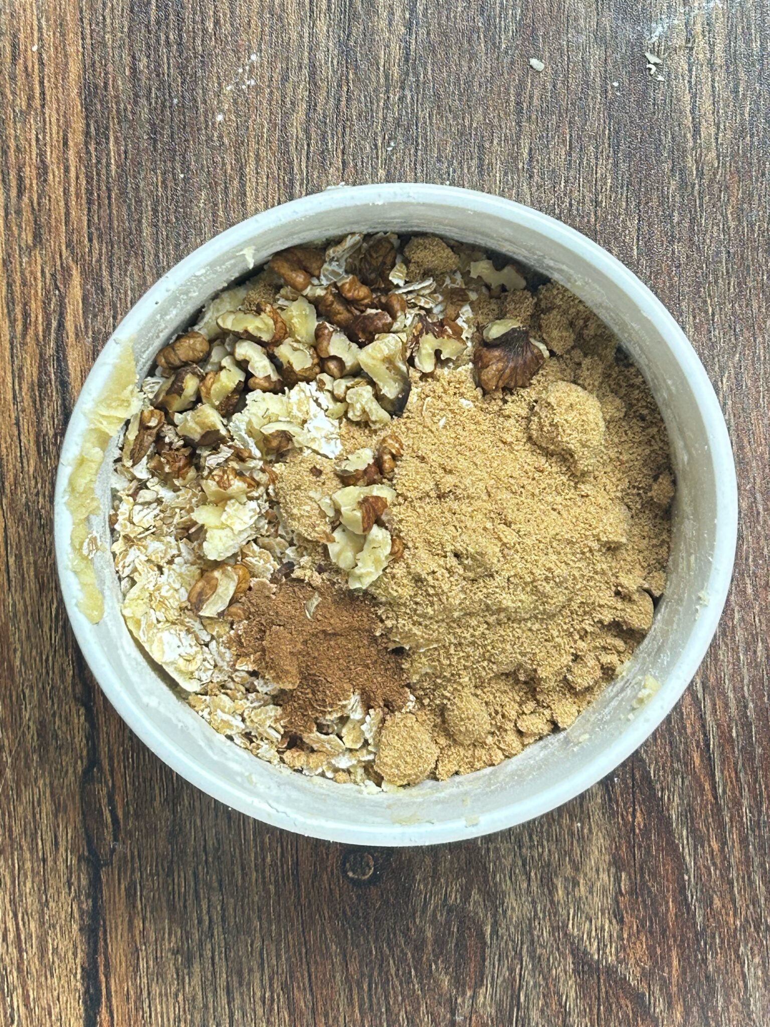 Adding oats, brown sugar, cinnamon and walnuts to the mixture Adding oats, brown sugar, cinnamon and walnuts to the mixture