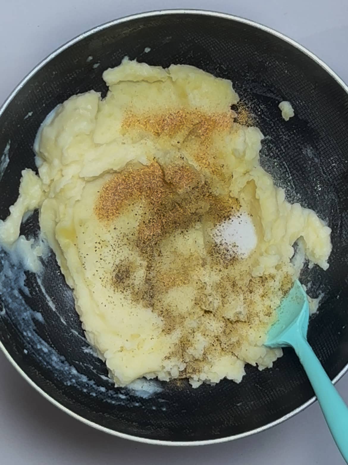 Mashing potatoes with milk, butter, and seasonings Mashing potatoes with milk, butter, and seasonings