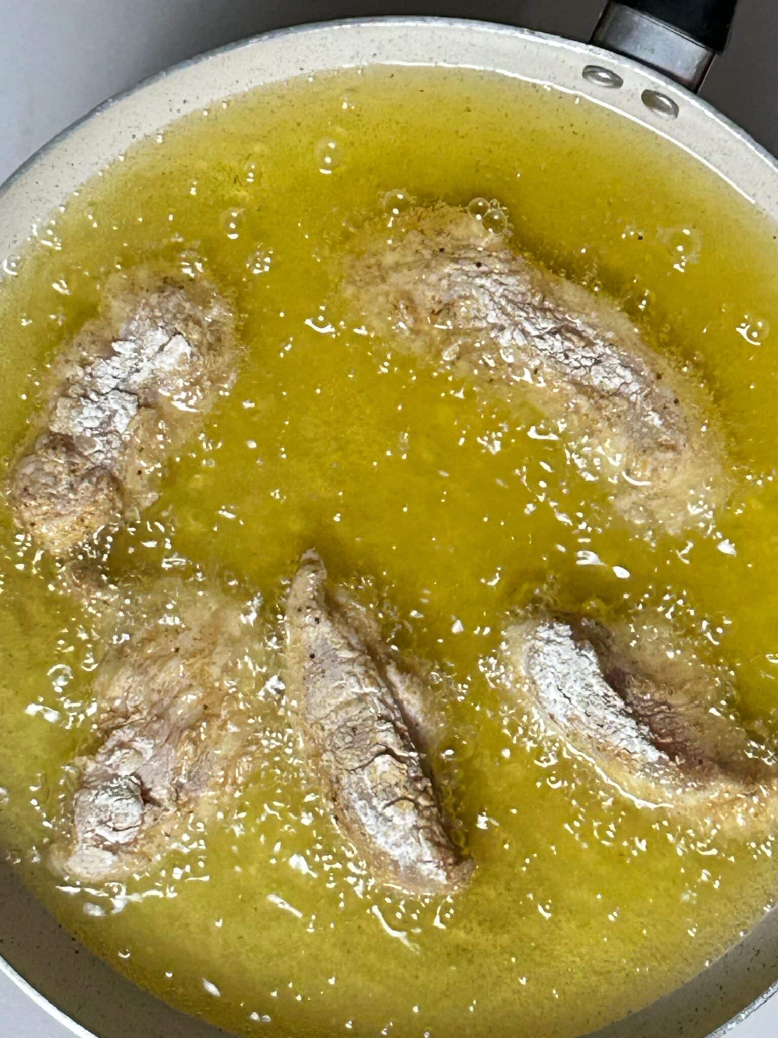 Chicken strips frying in hot oil using tongs until golden brown Chicken strips frying in hot oil using tongs until golden brown