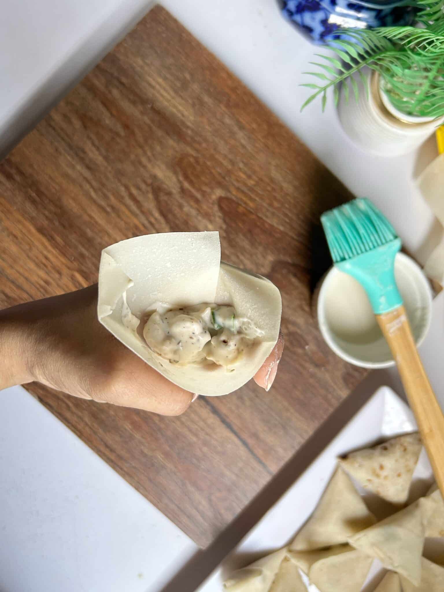 Adding Chicken Malai Boti filling into samosa sheets Adding Chicken Malai Boti filling into samosa sheets