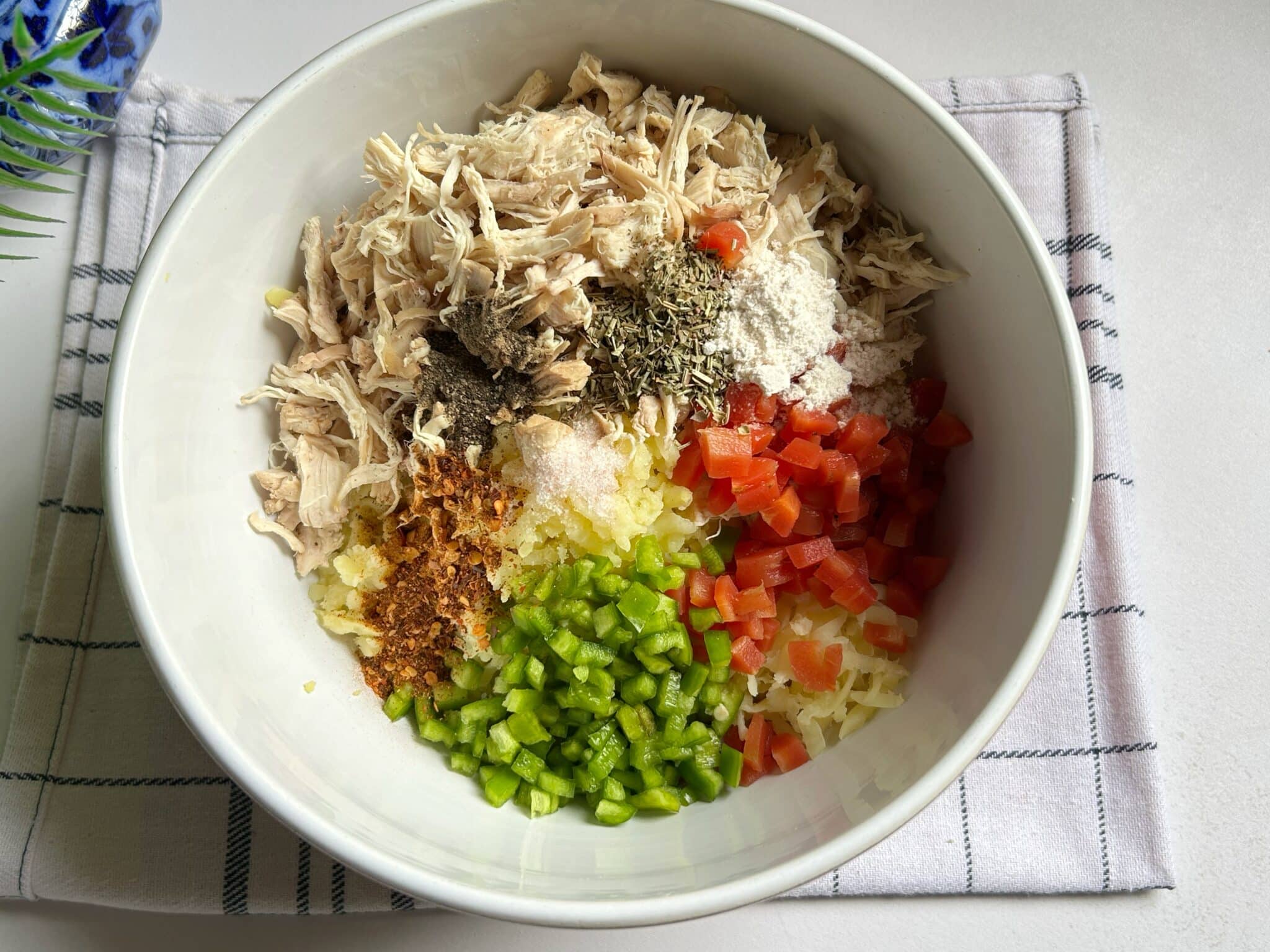 Mixing chicken, mashed potatoes, vegetables, spices, cheese, and egg for croquette filling Mixing chicken, mashed potatoes, vegetables, spices, cheese, and egg for croquette filling