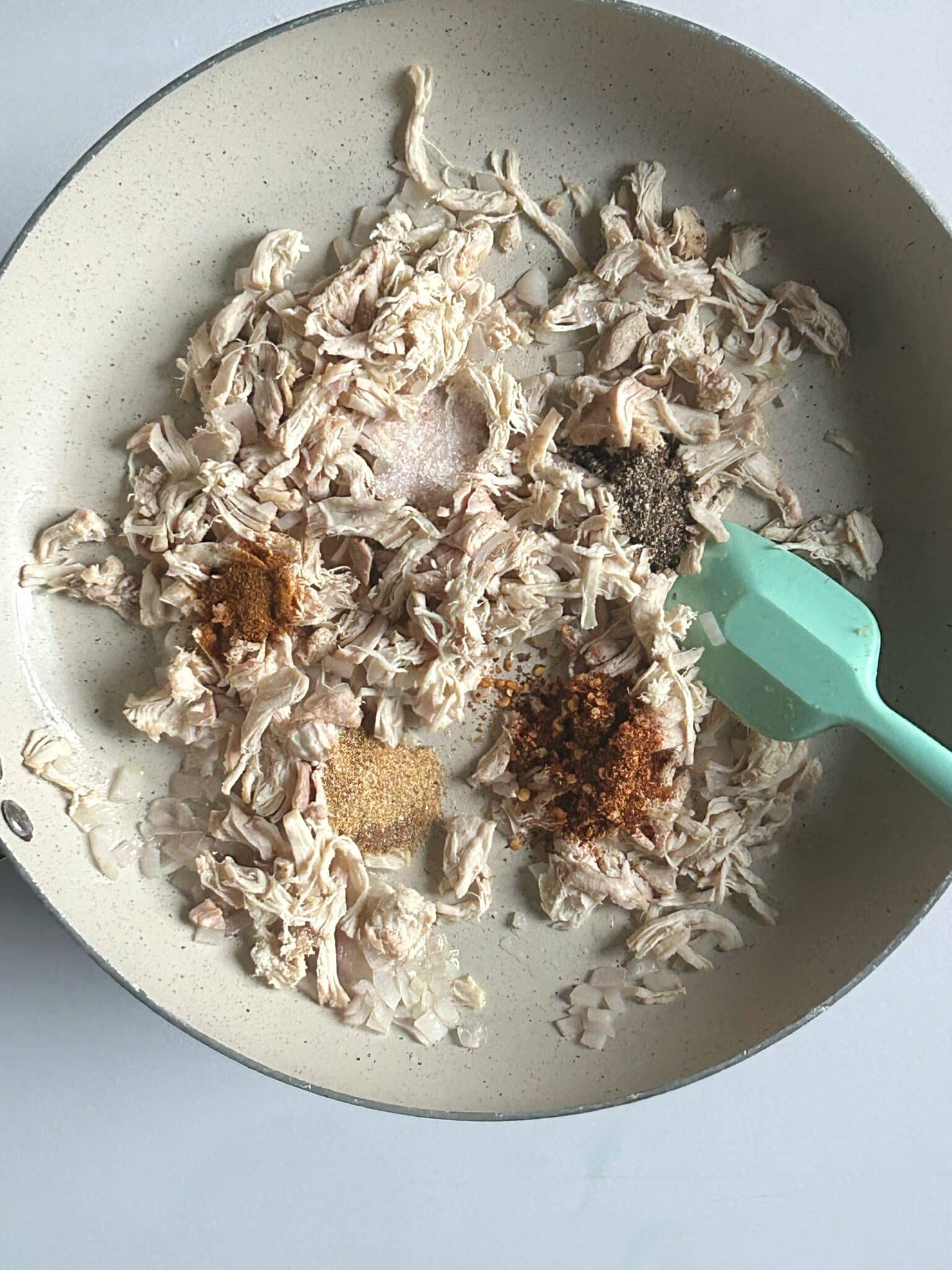 Chopped onions sauteed with shredded chicken and spices in a pan Chopped onions sauteed with shredded chicken and spices in a pan