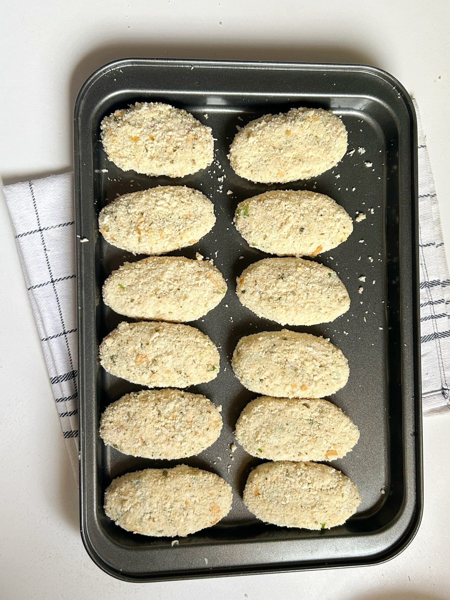 Rolling croquettes in flour slurry and coating them with breadcrumbs Rolling croquettes in flour slurry and coating them with breadcrumbs