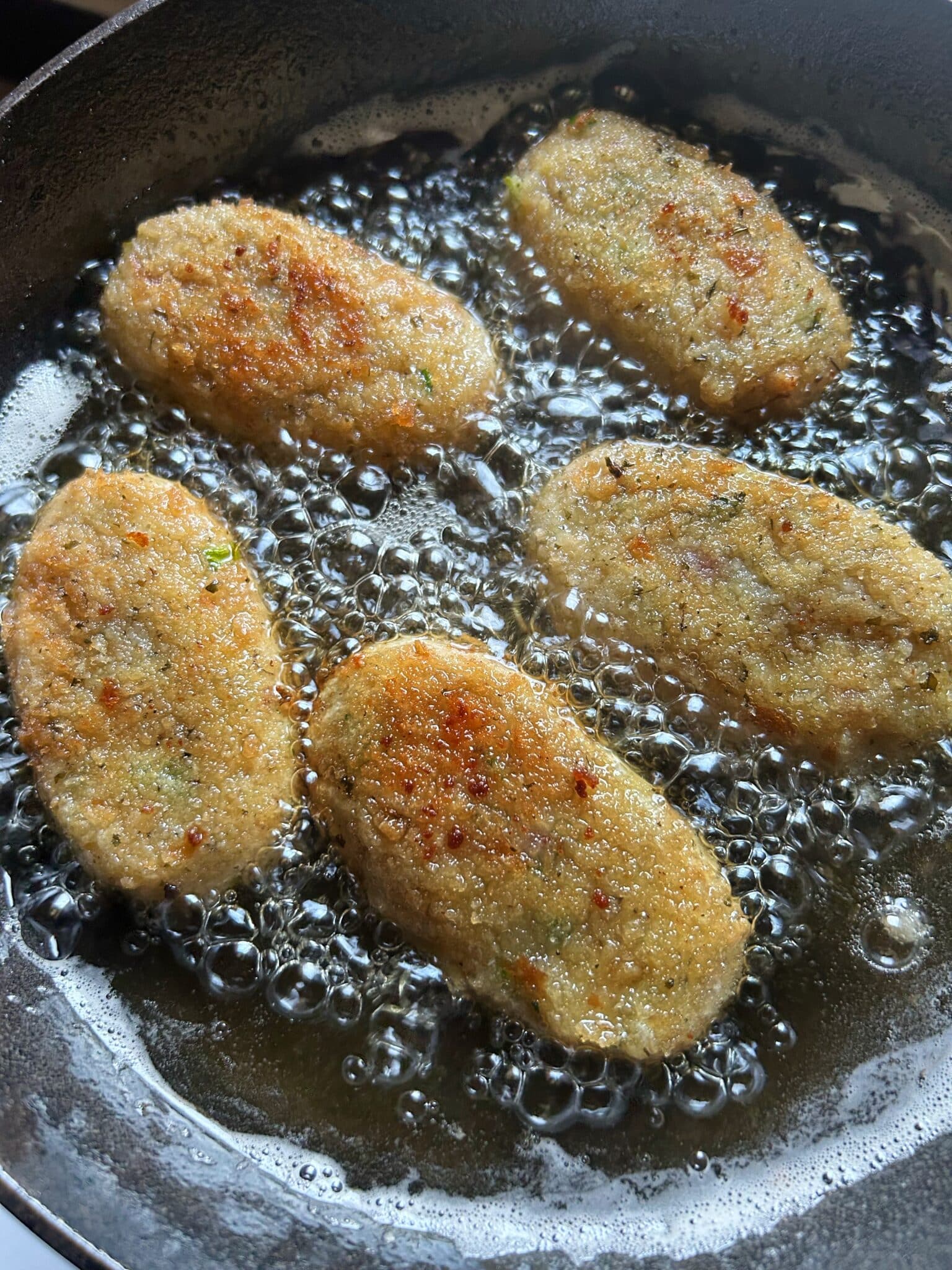 Removing golden brown croquettes from oil and placing them on a plate Removing golden brown croquettes from oil and placing them on a plate