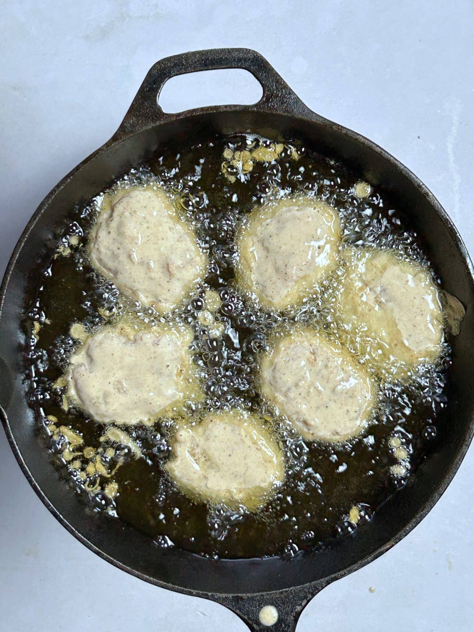 Preparing hot oil in a skillet for frying crispy homemade chicken nuggets Preparing hot oil in a skillet for frying crispy homemade chicken nuggets
