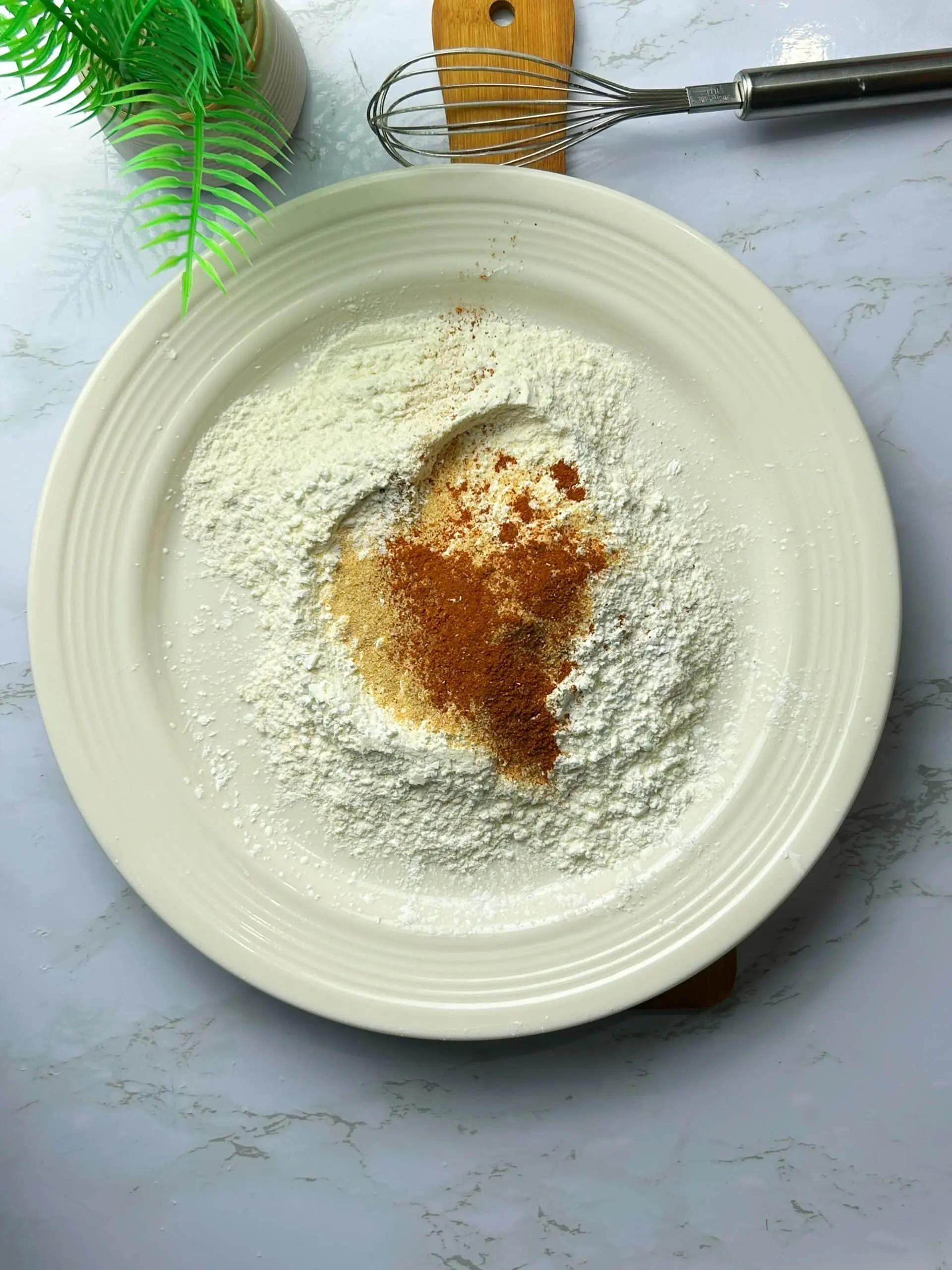 Flour, baking powder, and seasonings being whisked together in a mixing bowl