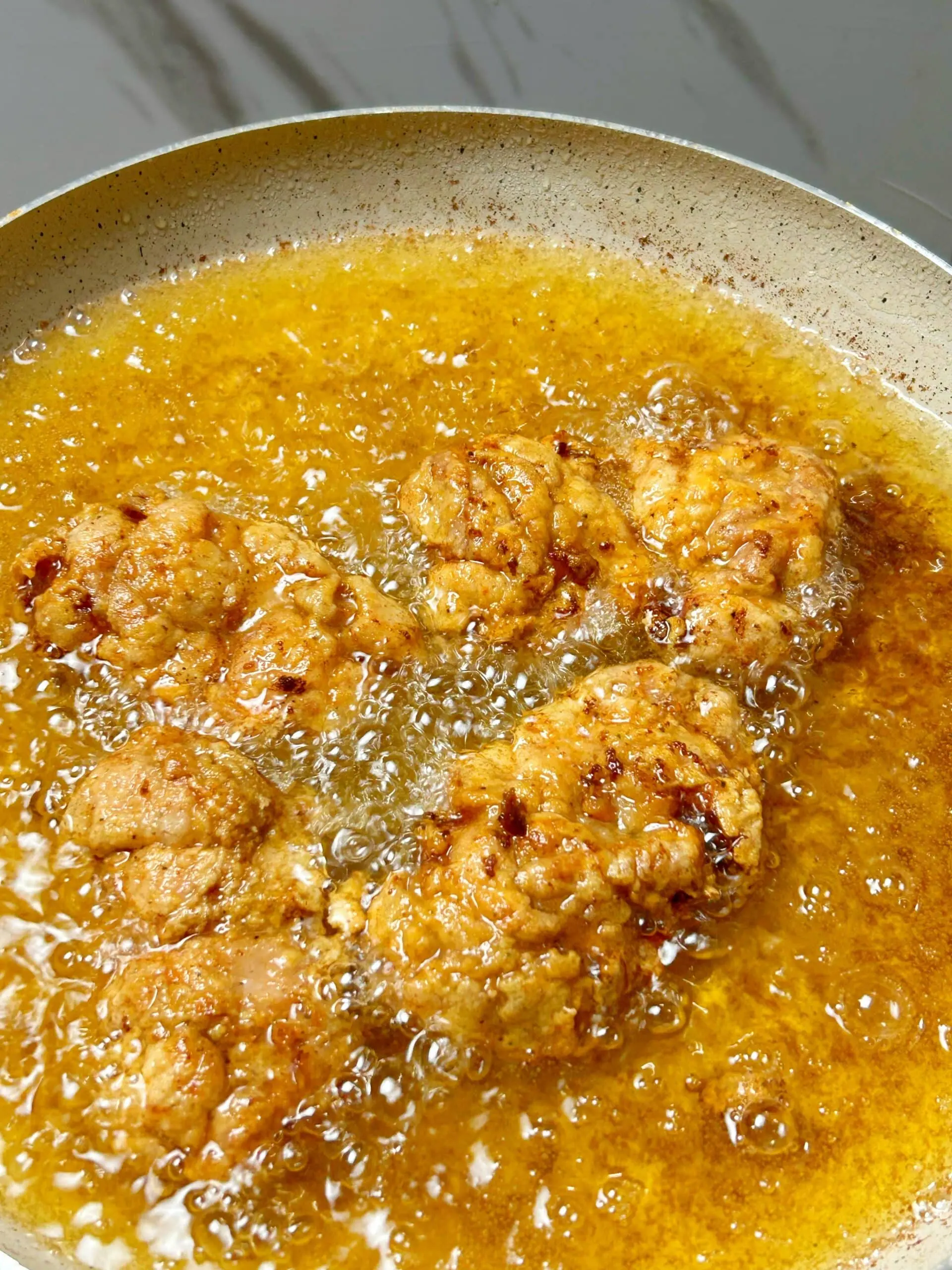 Chicken thighs frying in hot oil until golden brown and crispy